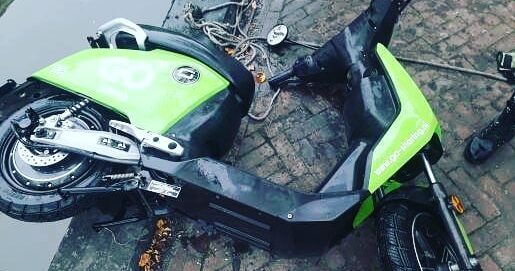 Groene deelscooter uit het water gehaald met een sterke bulldog vismagneet tijdens magneetvissen langs de kade.