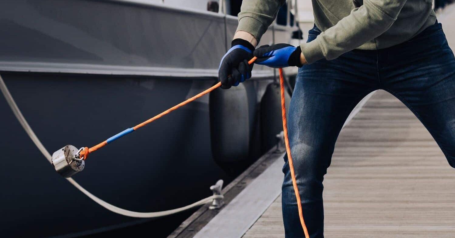 Een man die aan het magneetvissen is in de haven met een 360 magneet en oranje touw