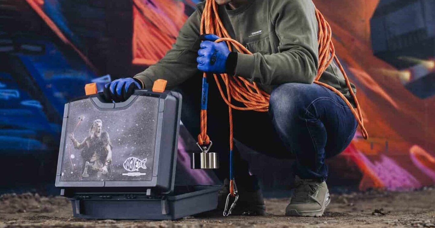 Een man die een vismagneet aan een oranje touw uit de koffer haalt