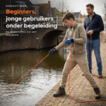 Lifestyle foto van een jonge beginner die onder begeleiding magneetvist langs een gracht